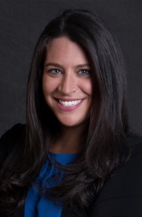 Headshot of young woman with dark hair on a dark grey background